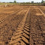 Terreno nivelado con huellas de maquinaria pesada en un campo al aire libre.